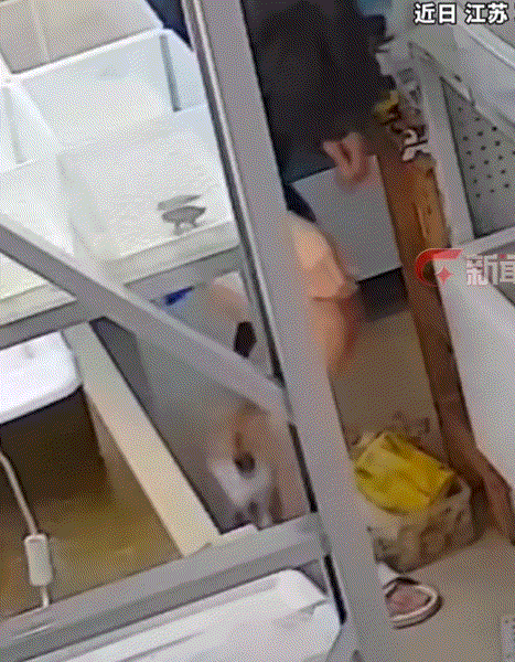 江苏苏州，一小伙坐在缸边逗耍眼前的小乌龟，不料其后方的大龟发现了他，并趁其不备之