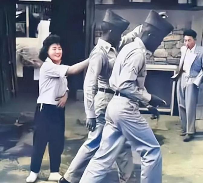 1952年，一名南朝鲜女子给两名美军做完服务后，当着老公的面热情地送大兵们离开。
