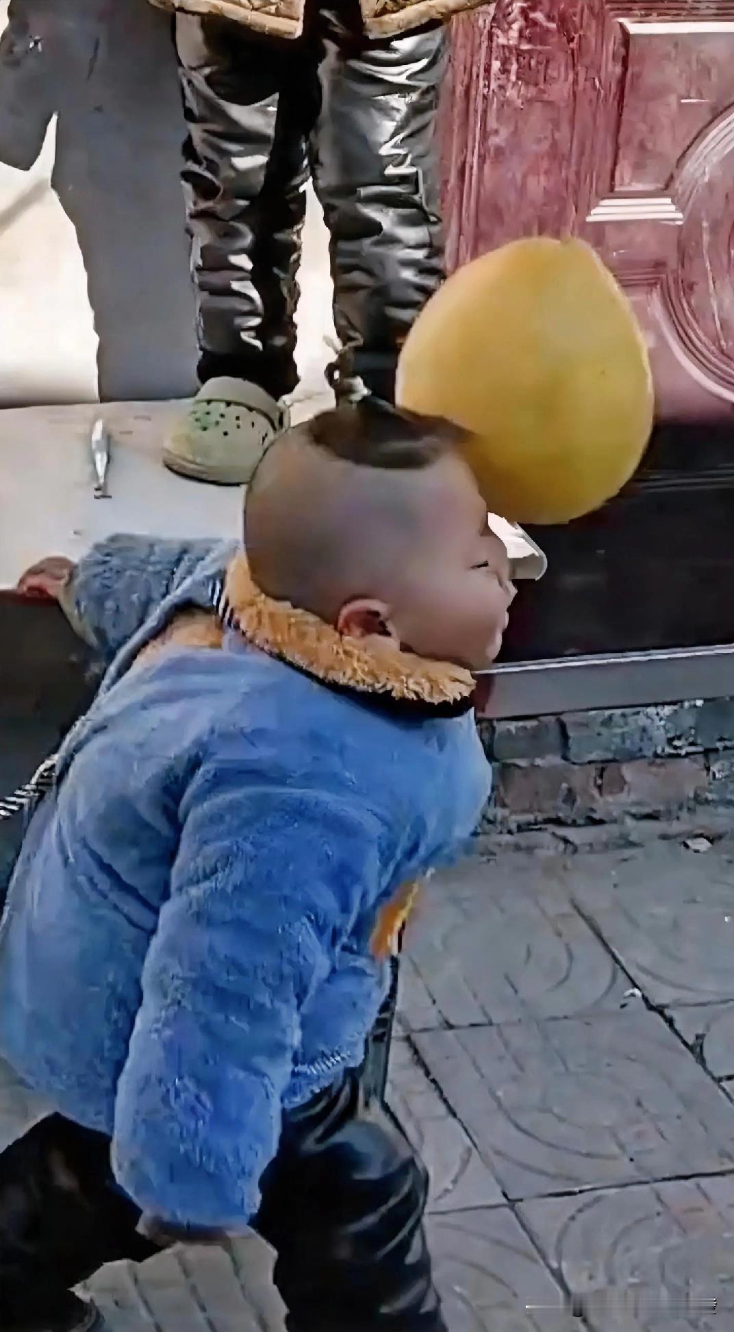 哥哥抱着一个柚子，站在院内桌子上，本来是想把柚子扔到地上摔开吃，可没想到的是，掉