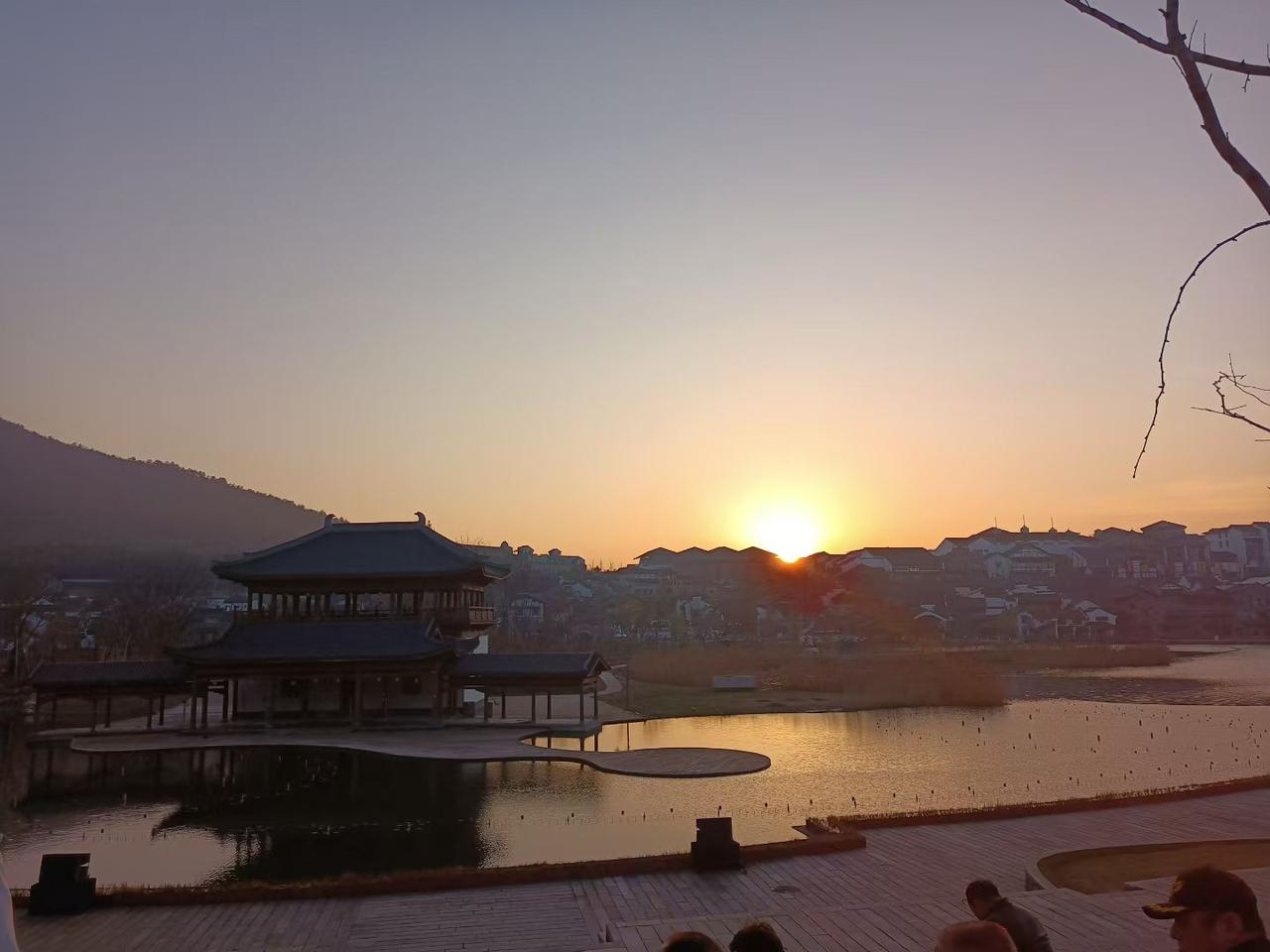 我拍到的落日瞬间日暮时分，夕阳把天空晕染成温柔的橘色。古建临水而立，波光潋滟，远