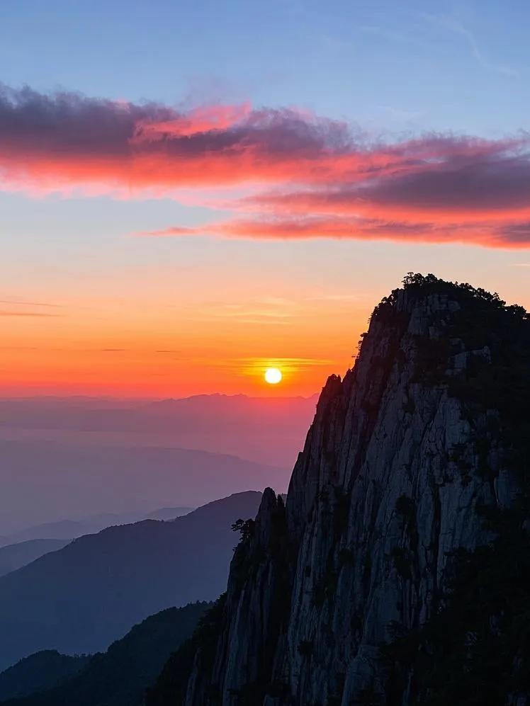 太阳西沉，庐山上空色彩层次分明，从炽热红到温暖橙，再到淡雅粉，与高处蓝天相映，视