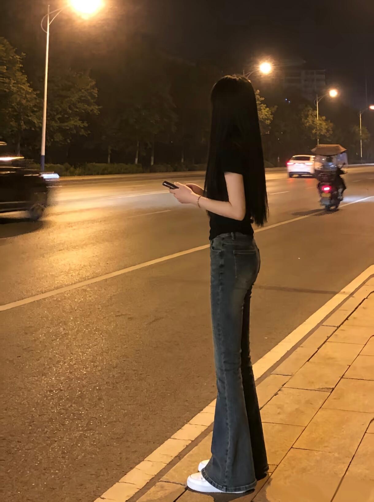 夜晚街头的独行者，手机里的世界与现实交错。