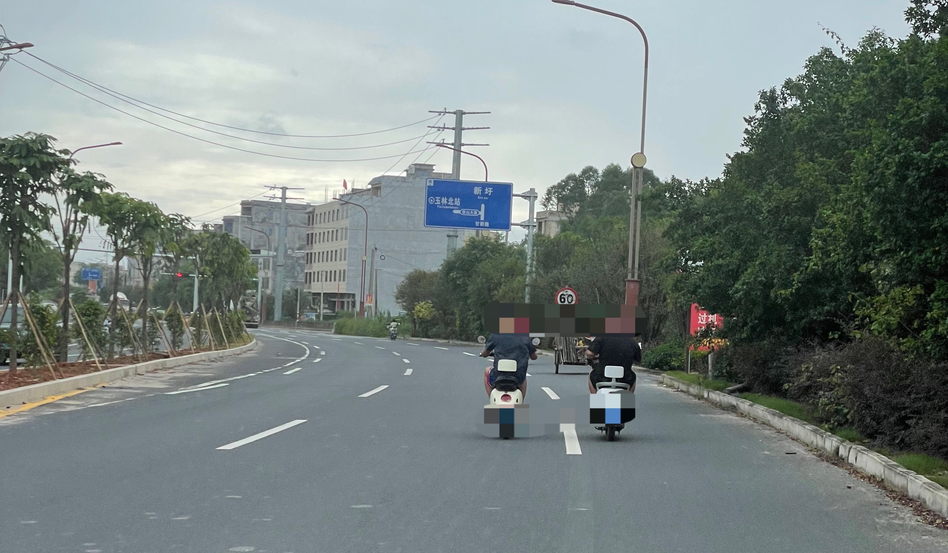 【玉林家具大街两男子并排骑电车】6月27日，玉林市北流家具大街两名青年男子一路并