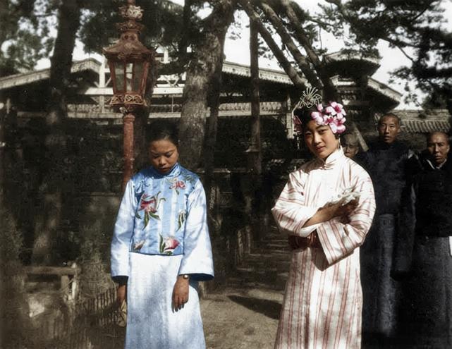 这张照片定格了逊清皇后婉容与淑妃文秀在紫禁城的日常瞬间，身后是宫苑里的古树，朱色