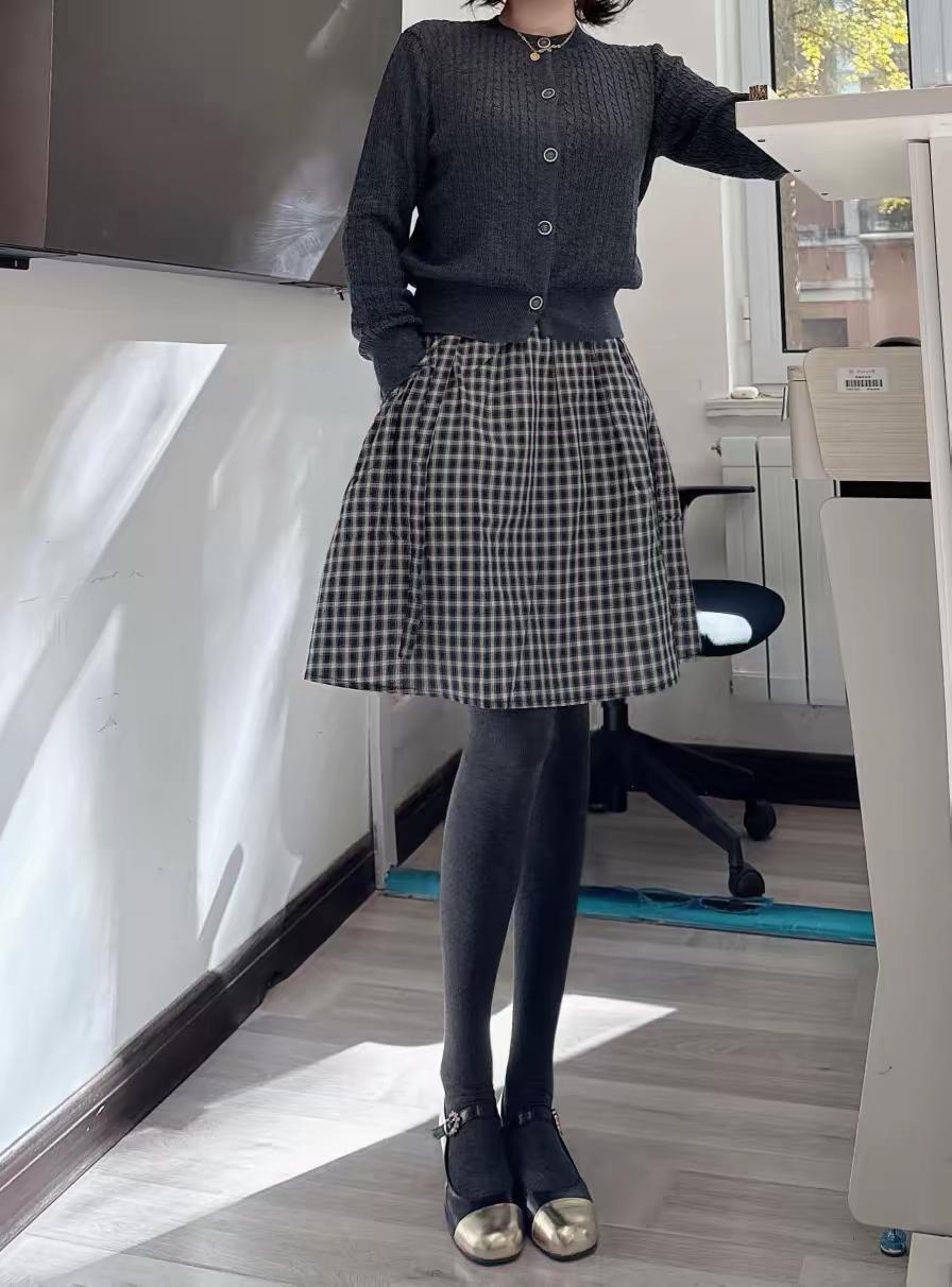 冬日灰调暖暖穿搭
上身是灰色带扣的毛衣，下身是格子百褶裙，腿上的灰色裤袜是羊绒的
