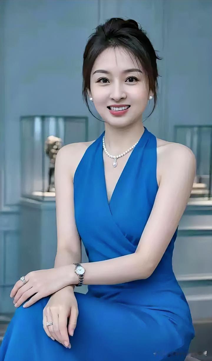 一袭湛蓝如深海般静谧，珍珠温润点缀颈间。她笑意盈盈，于雅致中流露从容，似画中人般