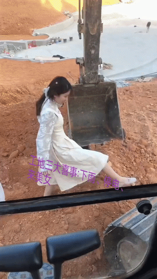 一名男子正开着挖机在施工现场干活。
这时有两个年轻女孩从他面前经过？
男子看到这