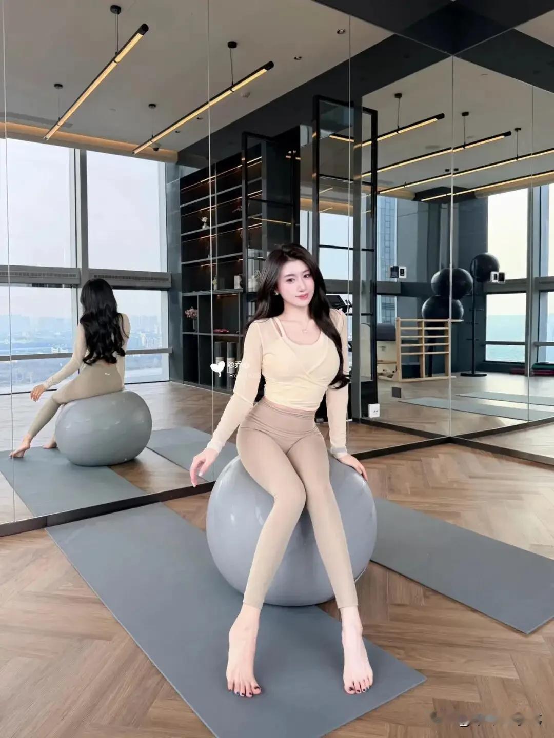 奶油交叉上衣配瑜伽裤
 
在全景落地窗的高空瑜伽室里，整面镜面墙把城市天际线尽数