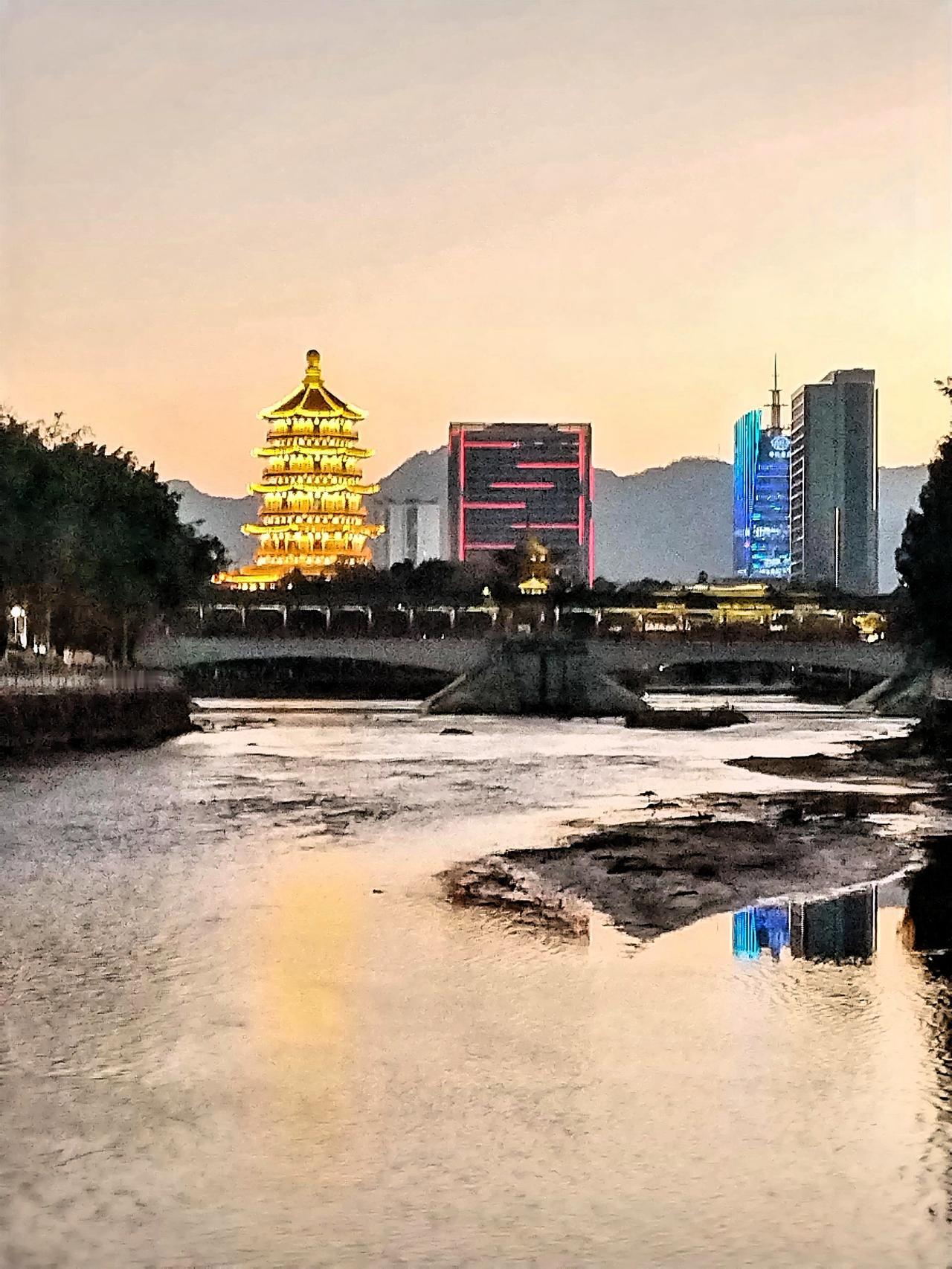 黄昏时分，灯火辉煌的塔楼倒映在静谧的河水中，城市与自然和谐共存。这如梦般的画面，