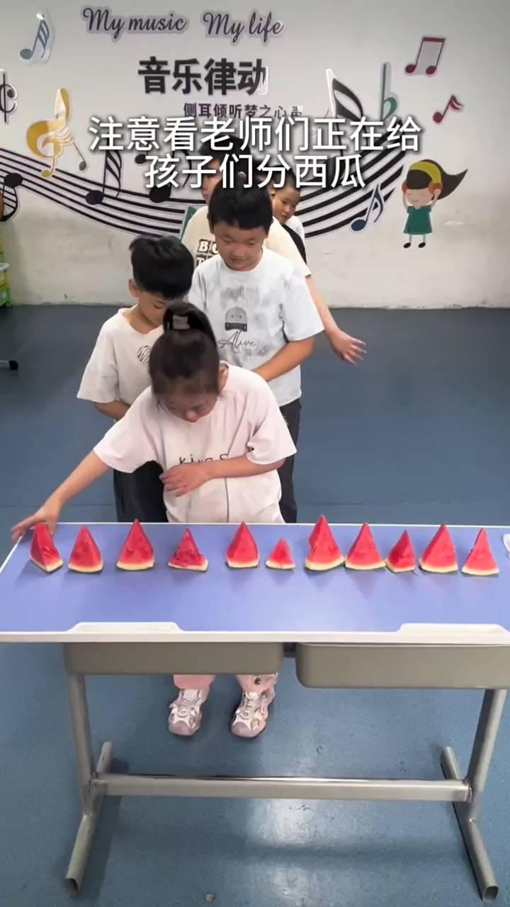 音乐律动。
注意看，老师们正在给孩子们分西瓜。前面的孩子不约而同都挑走了最大块的