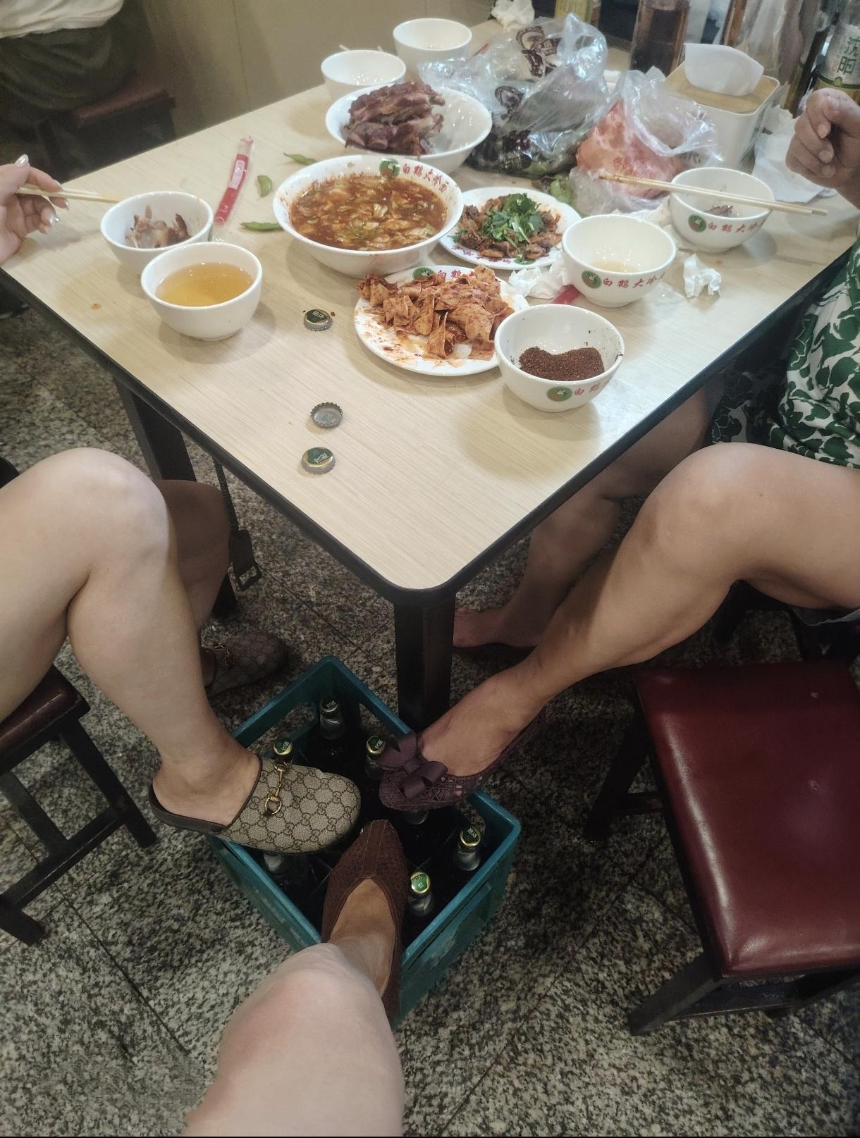 沈阳特色大冷面店，桌上有辣伴干豆腐，酱脊骨，拌毛蚶，大碗里是爽口泡菜圆白菜。女的