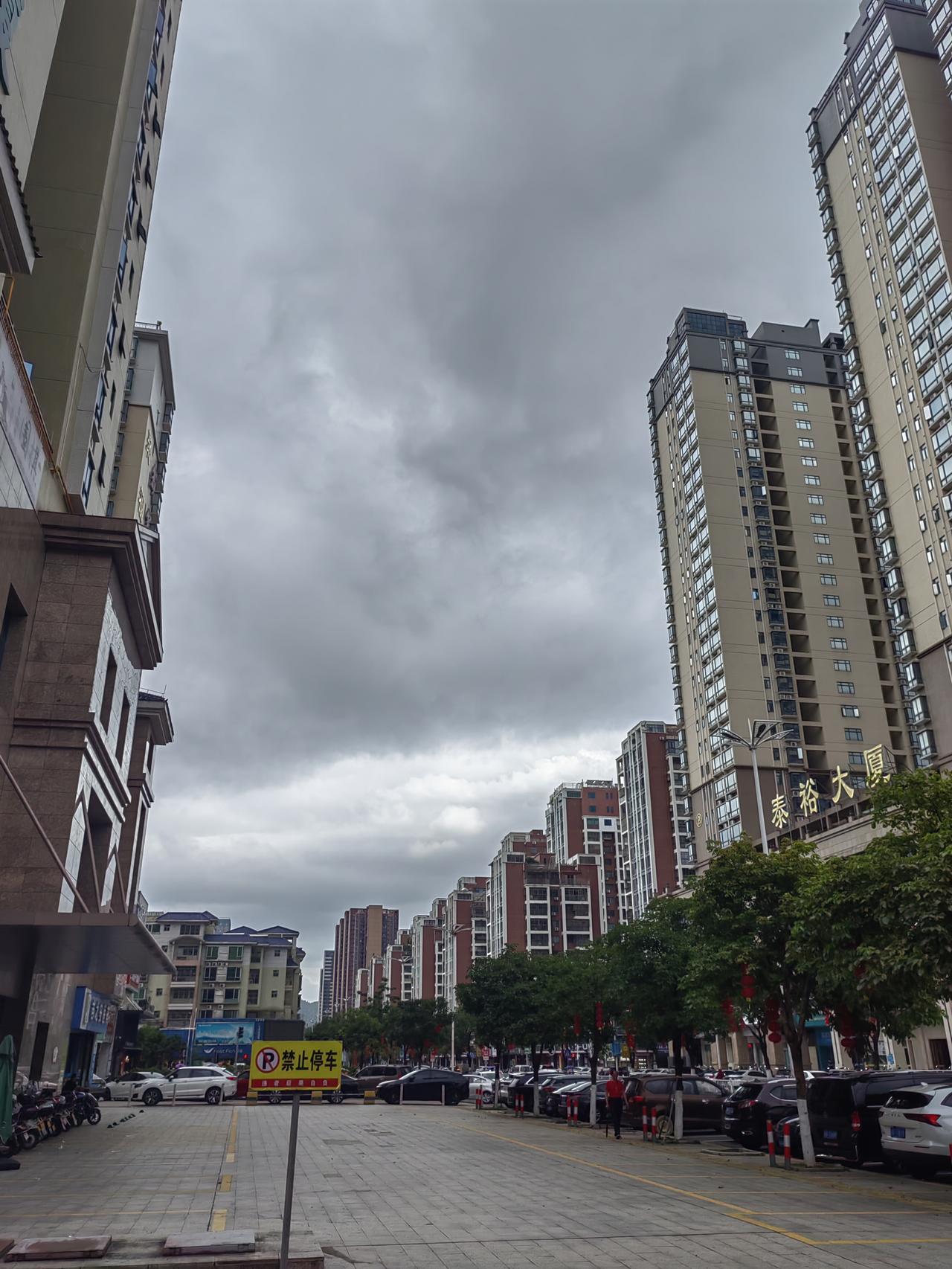 阴云密布下的城市街景，高楼林立，车流不息。