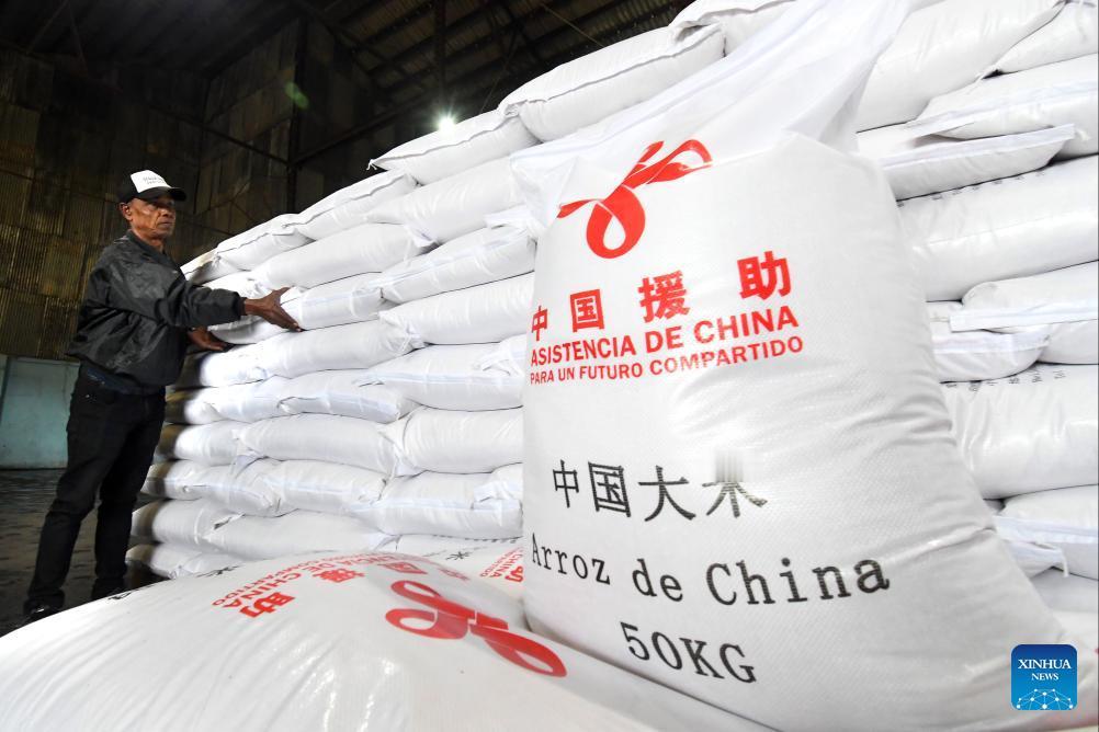 在古巴首都哈瓦那举行的援助物资交接仪式上，一名工作人员正在整理中国捐赠的大米麻袋