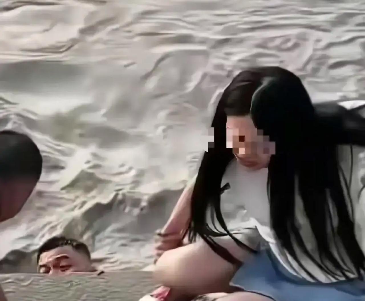 武汉汉口，一女子站在江滩边，丈夫给她拍照，突然丈夫扔下手机，纵身跳入江里。而妻子