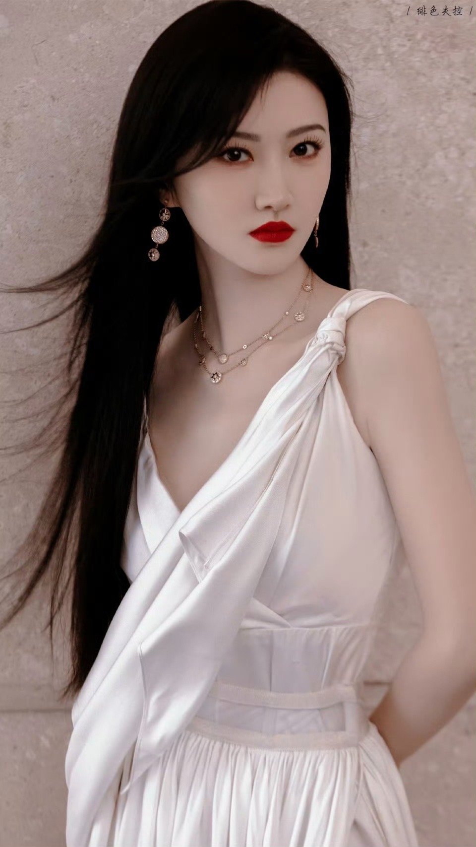 景甜身着一袭白色不对称长裙，垂坠面料如月光倾泻，独特剪裁勾勒曼妙身姿，高开衩设计