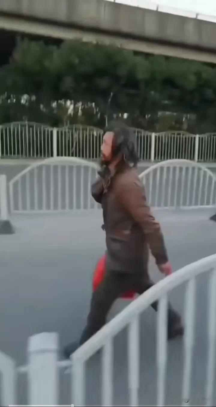 网友翻出了十几年前沈巍老师孤独一人行走在小镇路边场景。留着长发，衣衫褴褛，拎着一