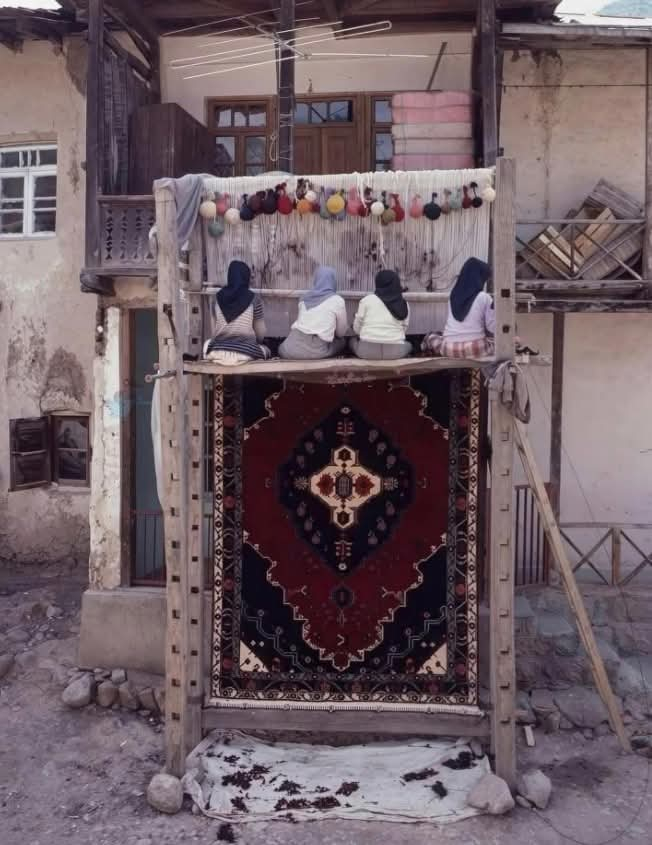 1989年，伊朗卡尚，妇女们正在一丝不苟地手工编织波斯地毯 