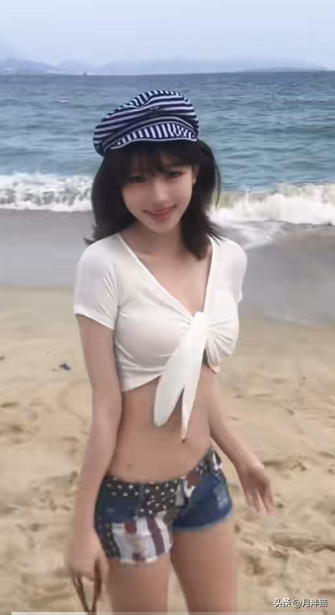 画面愈模糊，人愈发美艳。美女立于海边，身着休闲装，笑得极为开怀。她身着简约的白色