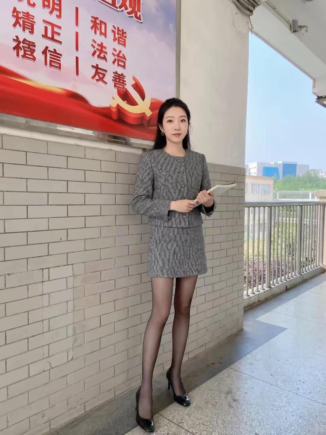 这女的一看就是体制内的，但是就是不知道这是老师还是公务员，一般情况下拿个书本站着