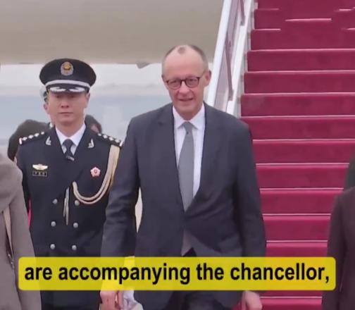 2月25日德国总理抵达访华第一站受到隆重欢迎，走在机场的红毯上，一位穿着军装的兵