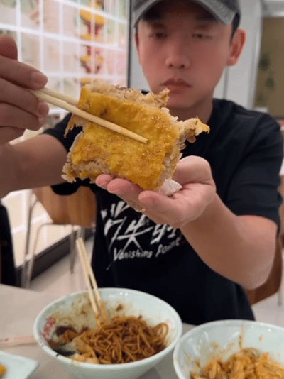郑恺一边骑车一边吃热干面 武汉过早新境界：边骑边吃，面不洒、酱不掉。郑恺用实际行