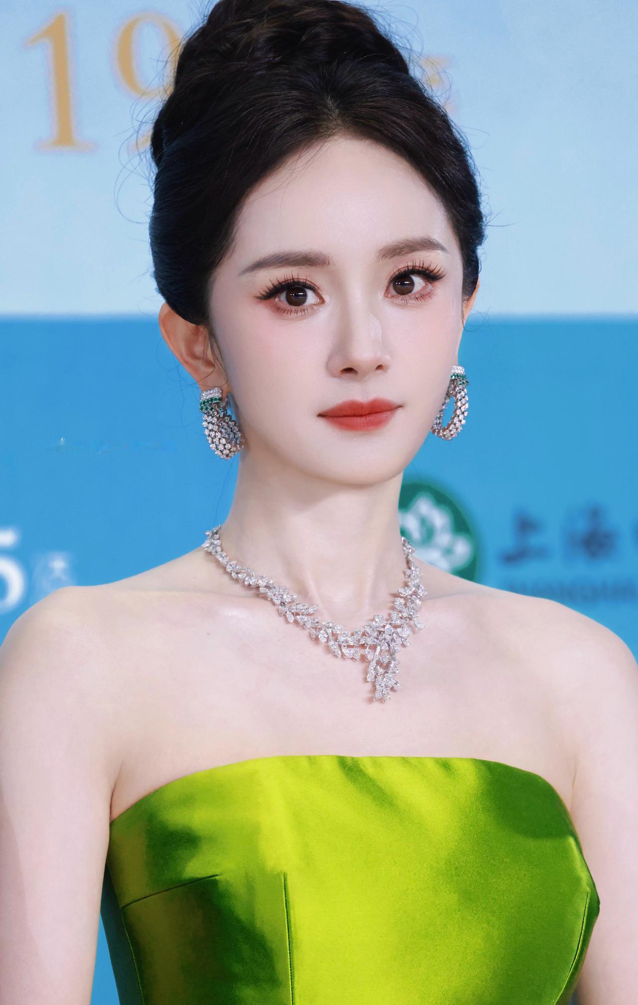 杨幂一袭竹叶青缎面抹胸，勾勒清晰优美的肩颈轮廓。

高盘发衬得脖颈修长，璀璨钻饰