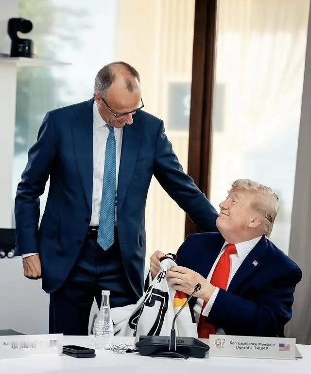 G7峰会上，德国总理默茨走到美国总统特朗普跟前，送给特朗普一件德国国家足球队的球