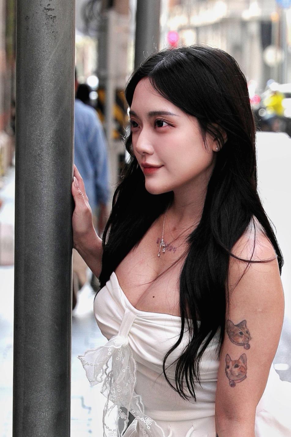 《红墙下的白裙少女》
白裙少女倚在红砖墙边，米白抹胸裙衬得她肌肤莹润，裙摆轻扬像