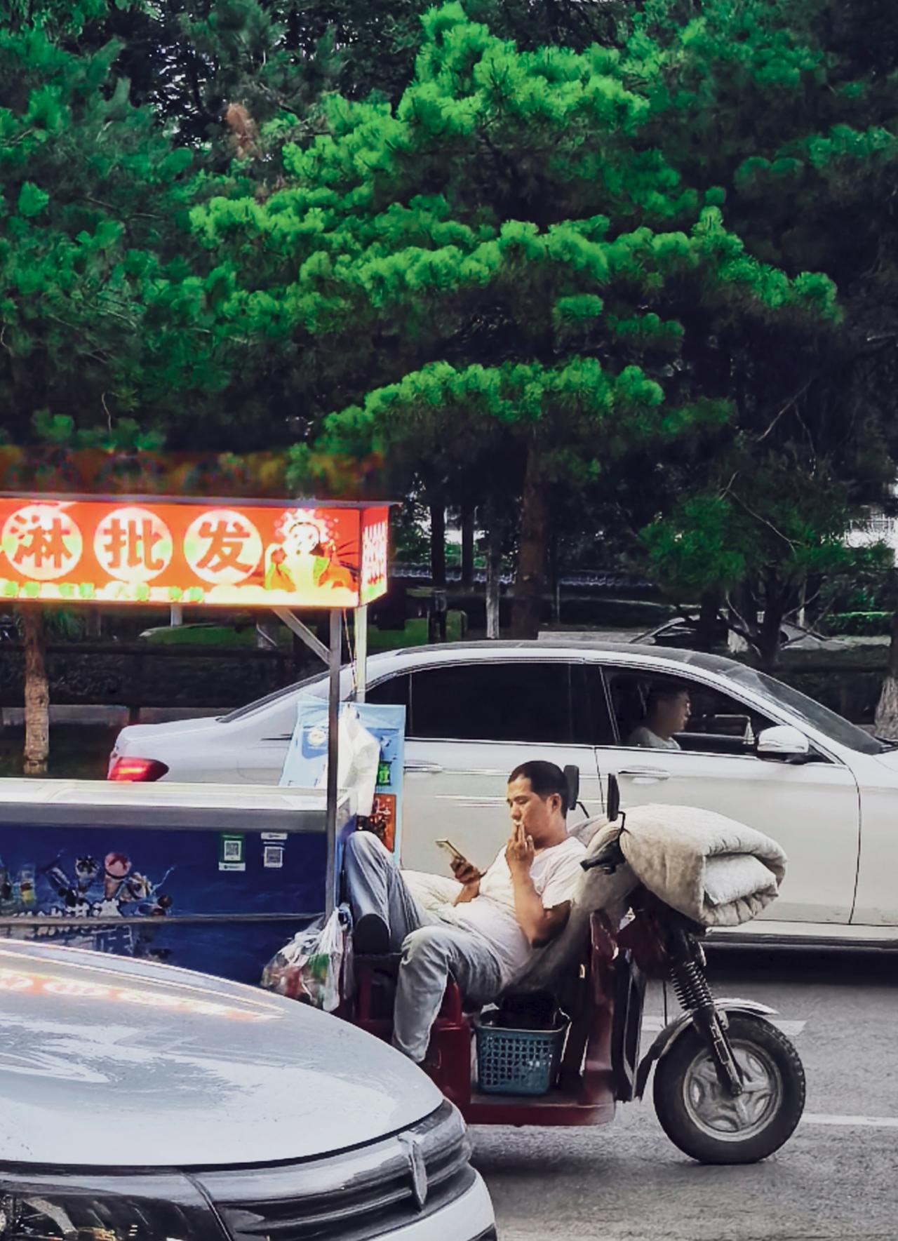 卖冰棍的大叔把三轮车变成了“移动沙发”，左手冰棍，右手拿着手机，生意做出陶渊明的