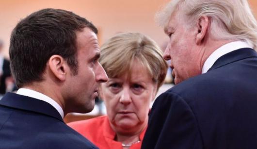 一张照片，三人面无笑容。美国总统特朗普，法国总统马克龙，还有德国前总理默克尔。他