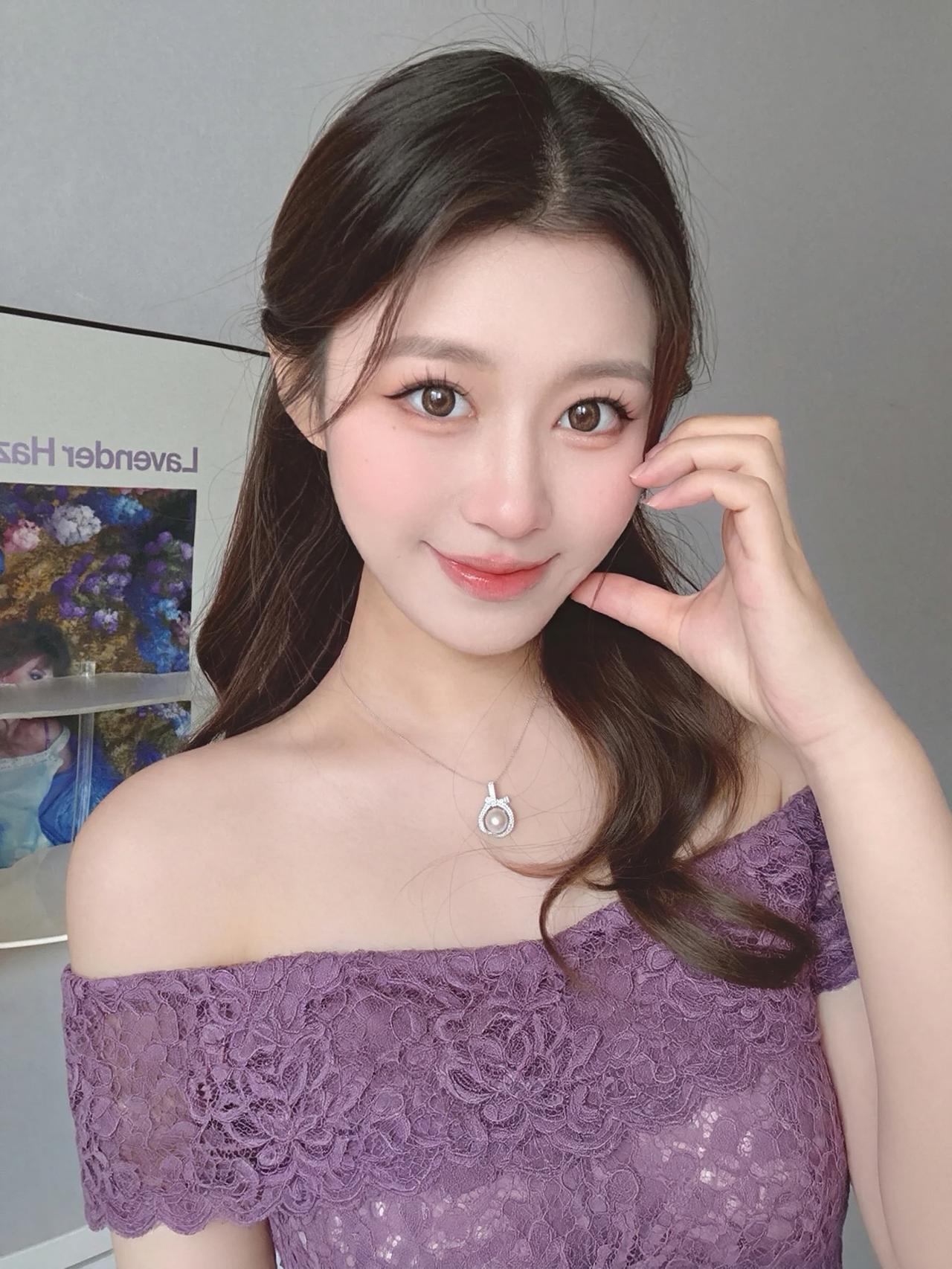 她留着一头深棕色的大波浪卷发，发丝蓬松有光泽，随意地披在肩头，慵懒又迷人。妆容清