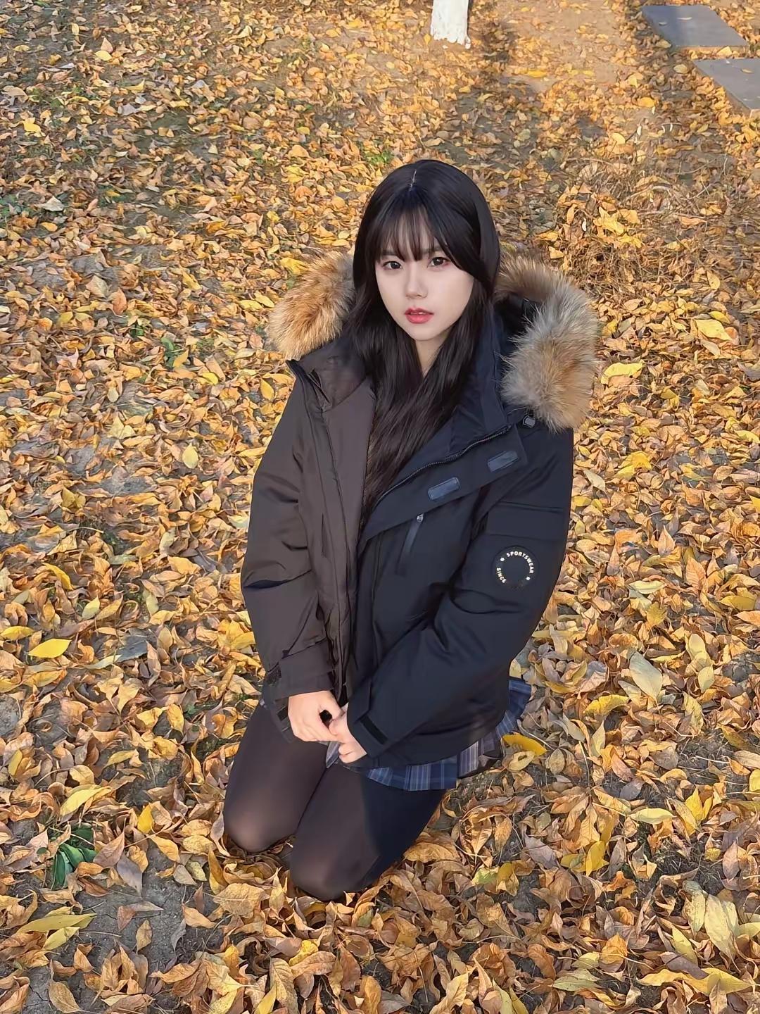 秋日暖阳下，黑发少女蹲在落叶中，温暖而宁静。