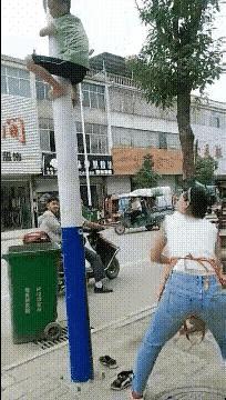 这个妈妈是疯了吧？孩子都被打的无处可逃了，已经爬到电线杆上面去了，你还要去打他，