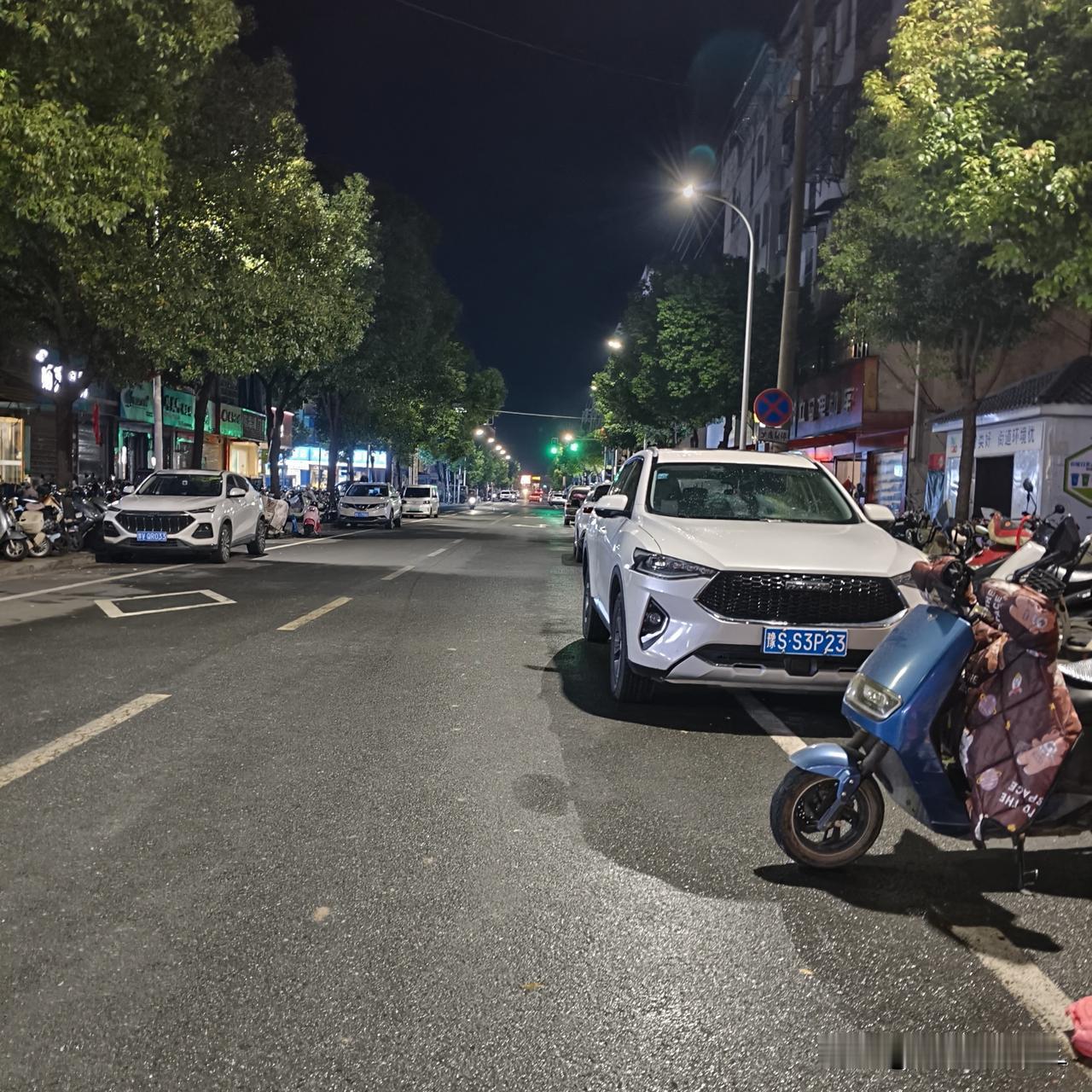 夜晚的街道上，车辆和电动车停放整齐。
