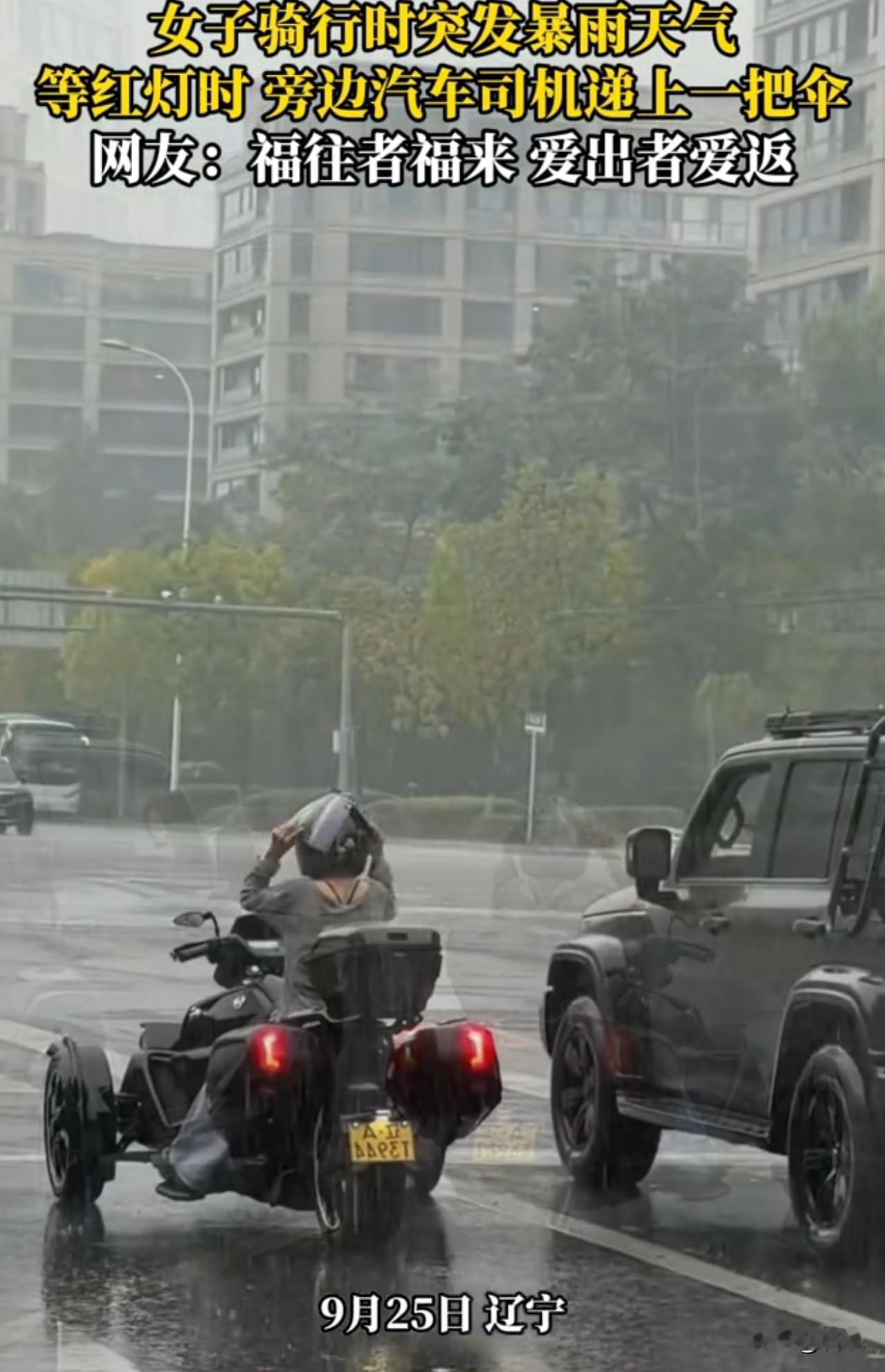 辽宁，一女子骑行时突发暴雨天气，等红灯时，旁边汽车递上一把伞。一看，开10多万的