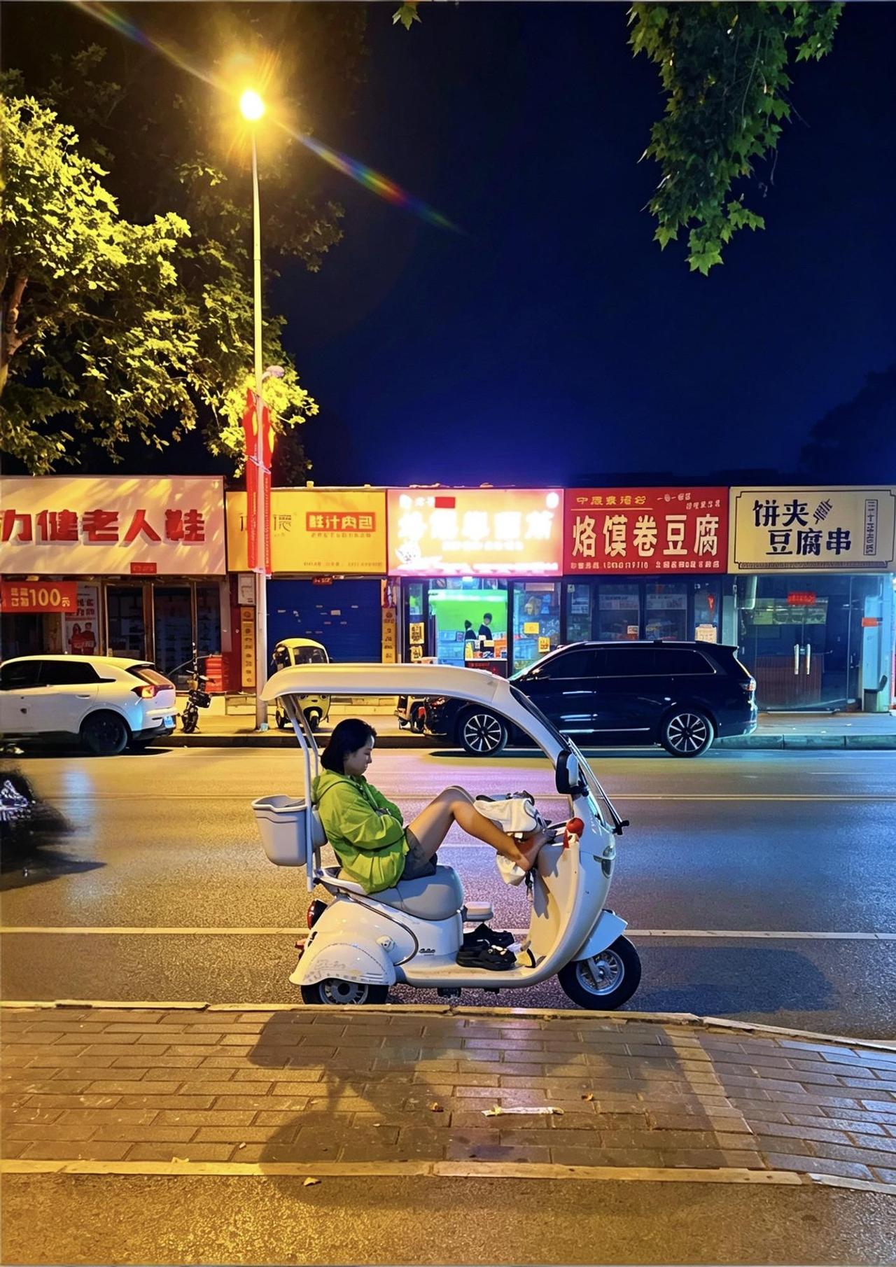 《夜街闲趣》
长檐轻车倚路隅，青衫慵坐晚风徐。
纤足漫搁银车柄，丽态天成自有姝。