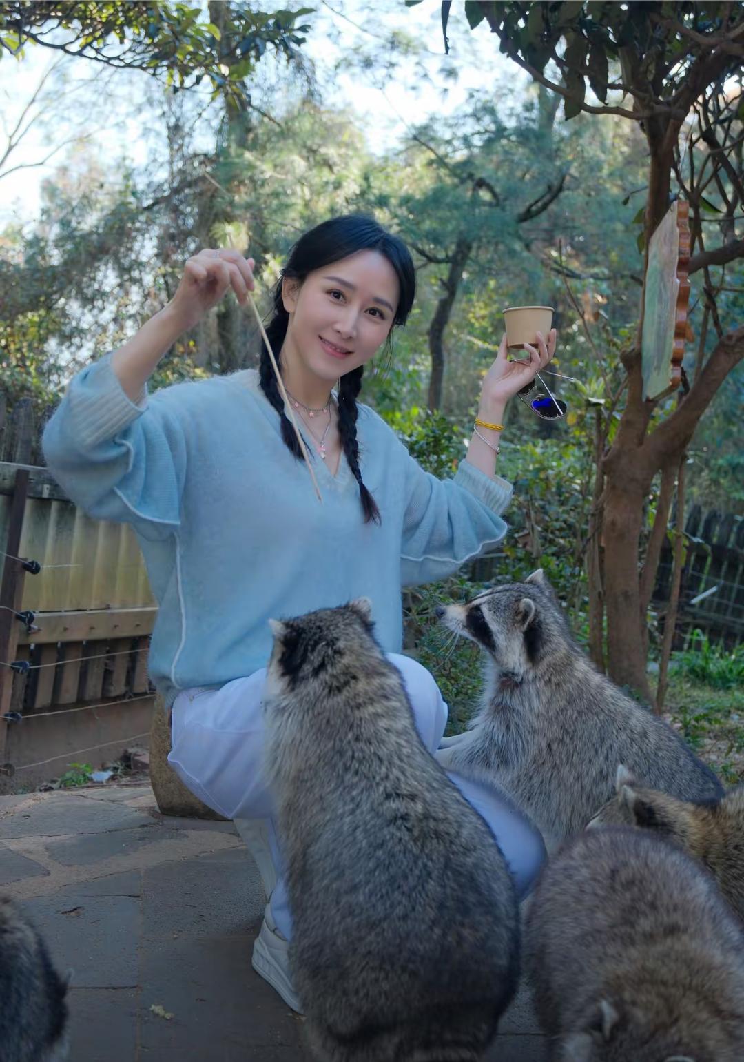 胡静打扮得像青春少女在云南野生动物园玩，她梳着两个麻花辫，穿着浅蓝色衣服，白色裤