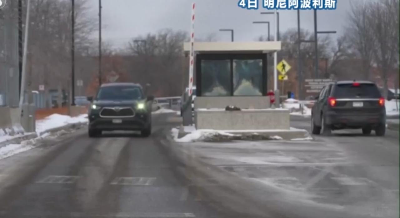 明尼阿波利斯的街头，铁网隔开了对峙的人群，执法车辆在路口严阵以待，岗亭旁的车辆缓