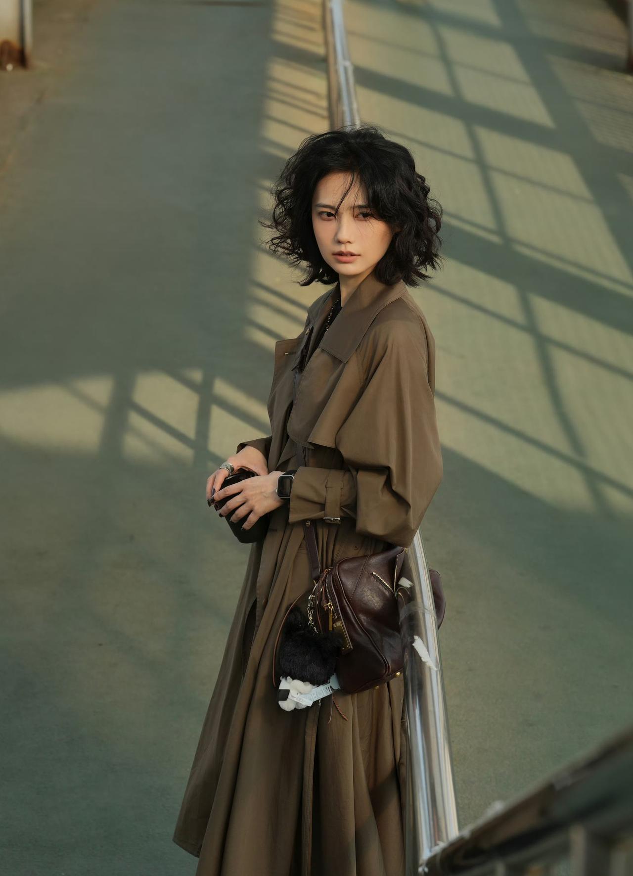 谁说风衣只能穿得刻板？微卷短发+大地色系风衣，再配上一只复古皮包，松弛感和高级感