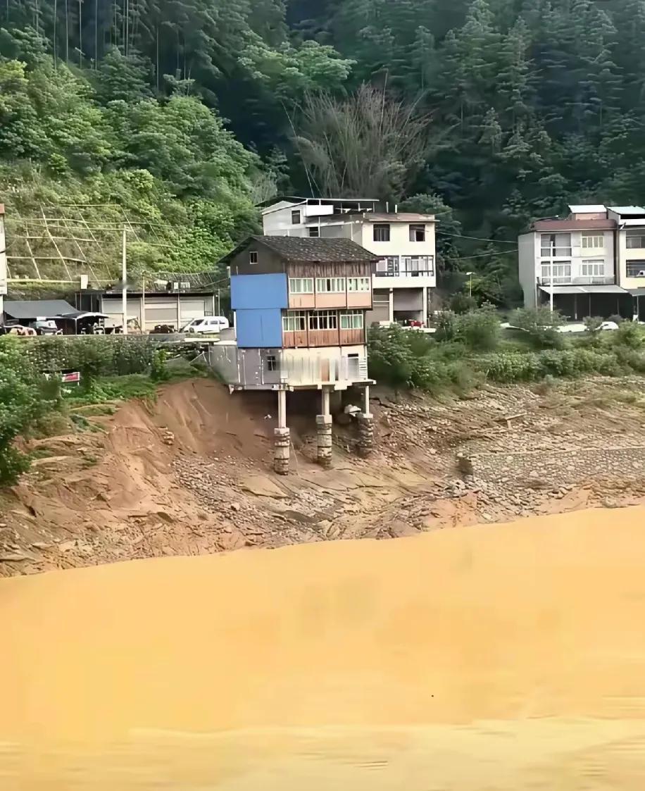 盯着这栋戳在河坡上的房子，我后槽牙都跟着紧——几层楼的屋子，就靠几根柱子支在黄泥
