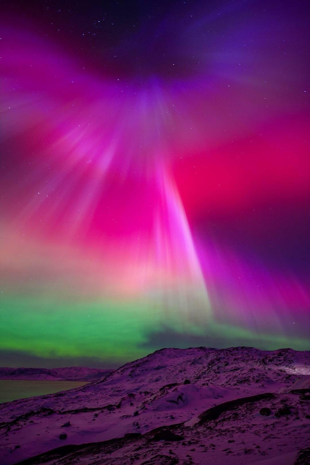 1月20日凌晨南格陵兰卡科尔托克的夜空中，玫红色与紫红色的极光如瀑布般倾泻而下，