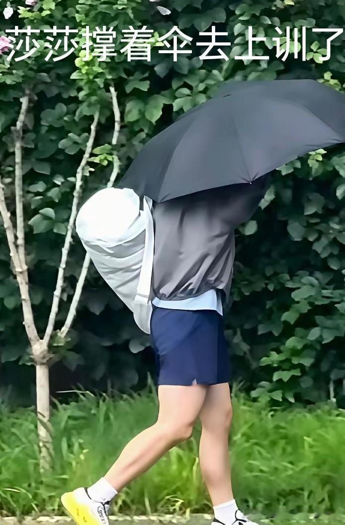 今天北京下着小雨，有球迷拍到莎莎撑着一把黑色的伞，挎着小白包去上训了！

虽然没