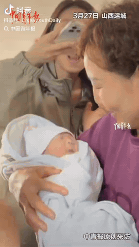山西运城，一女子在产房生产后，护士抱着孩子出门，一家人全都围上去拍照逗孩子，可这