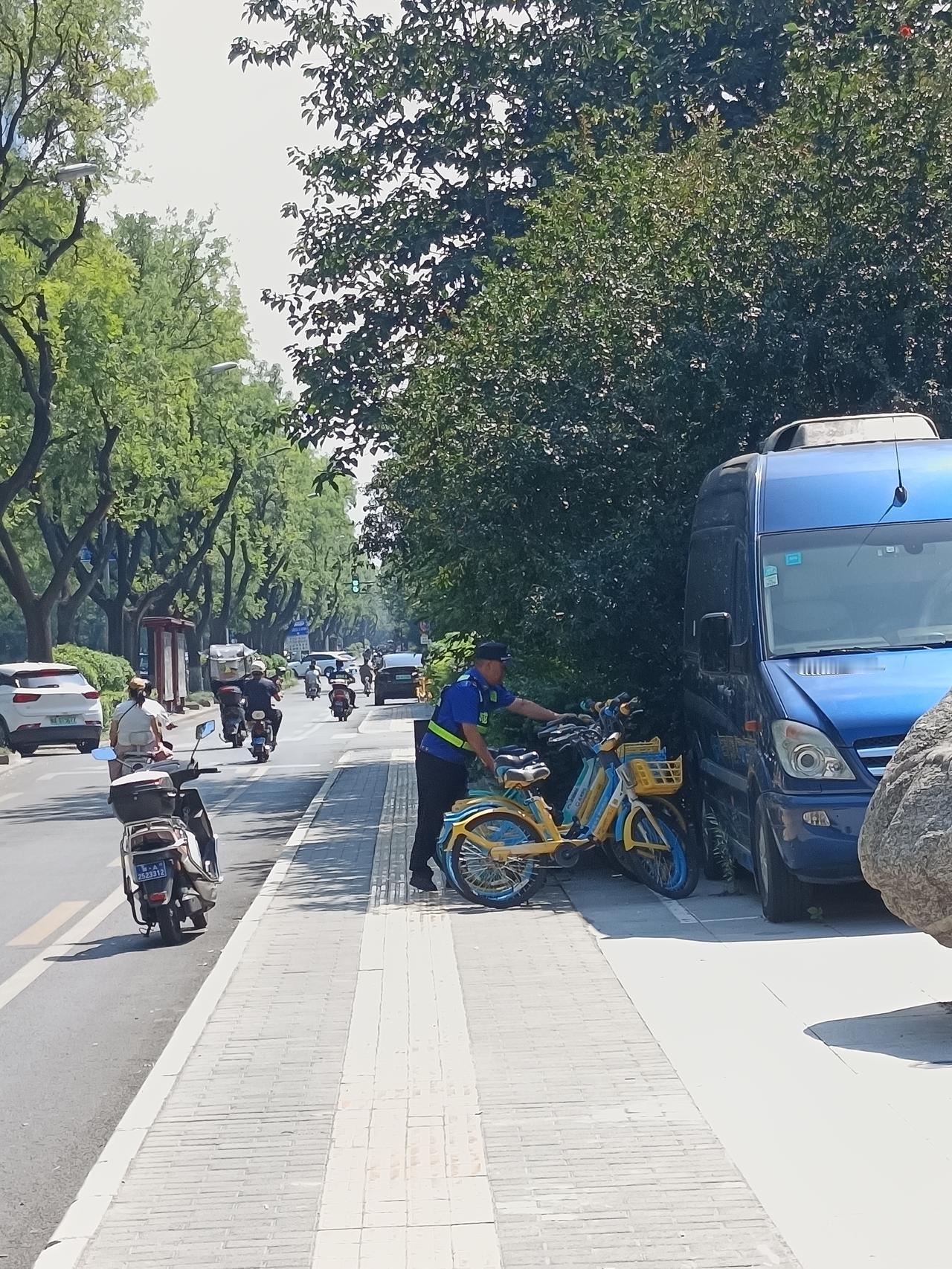 小雁塔附近，有几位城管队员，骑着电动车，看见路边乱停乱放的共享单车，自己动手摆放