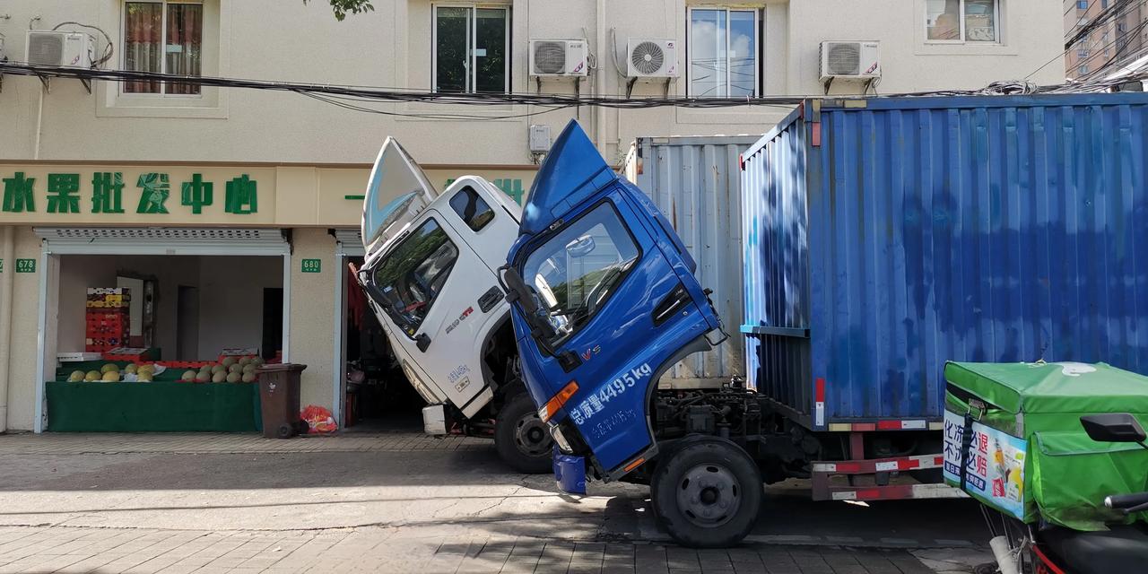 两辆厢式货车，满载水果，千里迢迢送到了目的地。
不知为何，两辆车的车头都被掀起来