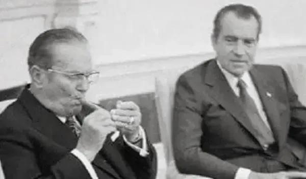 铁托坐在椅子上，翘起二郎腿，嘴角含着一根雪茄。烟雾缭绕，尼克松在对面，眼神复杂地