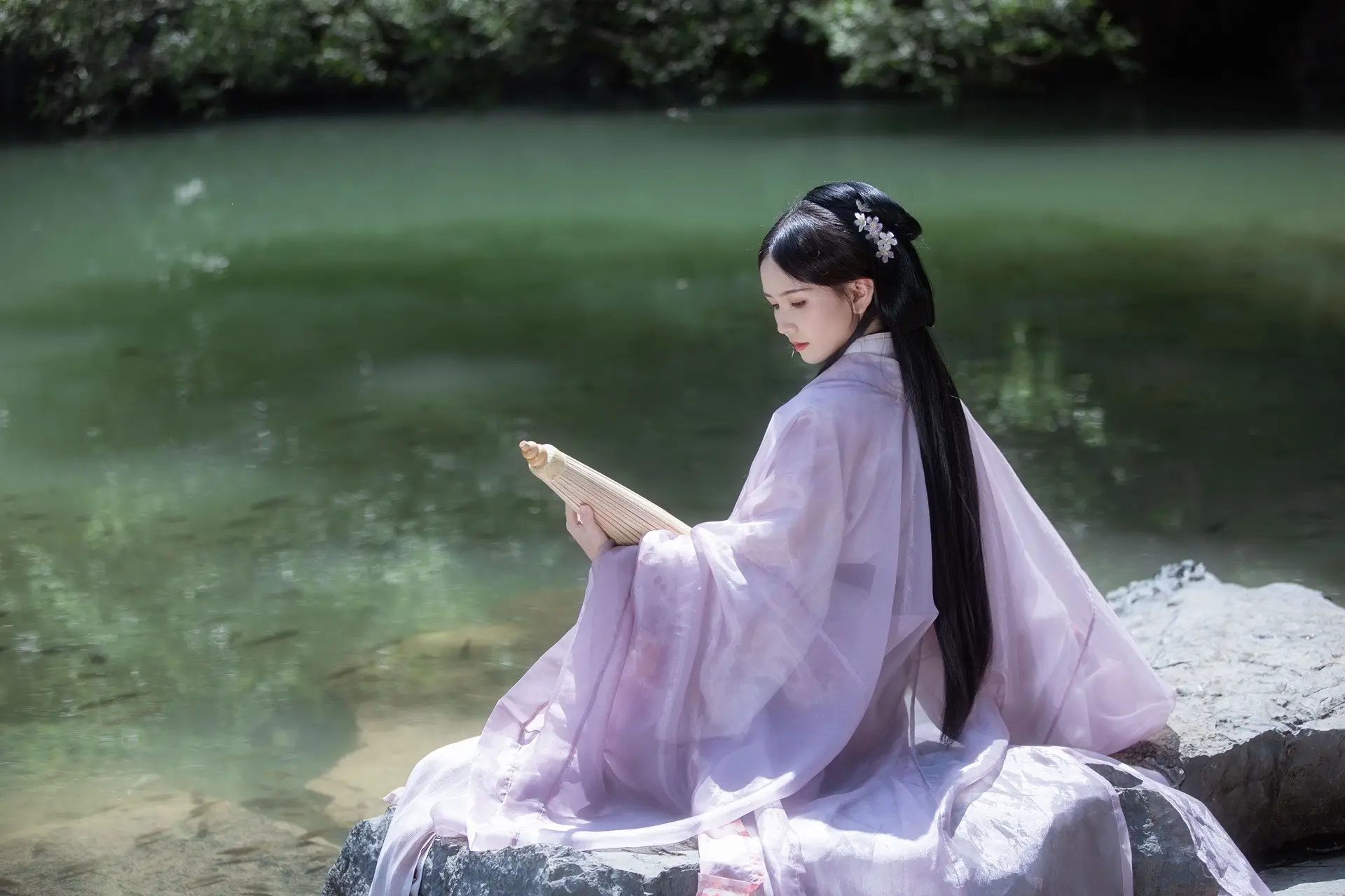 "青伞轻摇绿水边，紫衣倩影画中仙。"