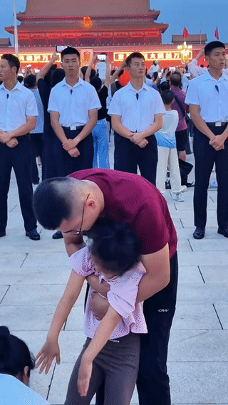 北京天安门广场上。
升国旗仪式即将开始。
爸爸赶快搀扶起正在睡觉的女儿。
试图叫