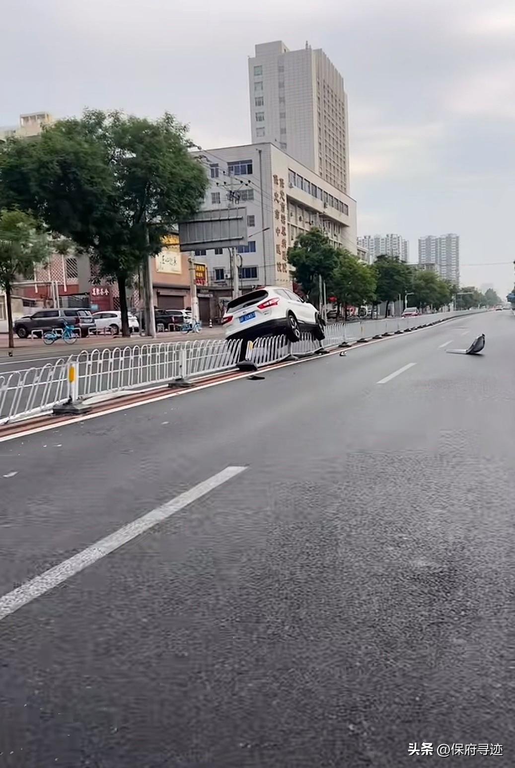 今天保定市区一道路上又出现了惊险的一幕，只见一辆白色的SUV直接骑在了护栏上，而