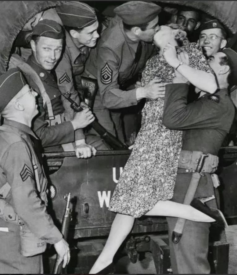 "1940年代，一名士兵举起一名年轻的女人，将她送给卡车上的大兵。这名大兵不但亲